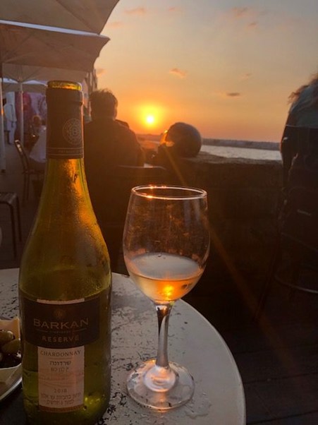 A glass of Chardonnay from Barkan Winery with the beautiful sunset in Tel Aviv. Photo Credits: www.wineprincess.it
