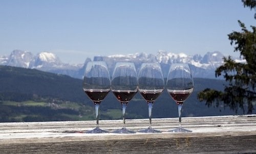 Four glasses of Lagrein and Schiava, great red wines of Trentino-Alto Adige.In the background the Dolomites. Photo Credits: www.identitagolose.it